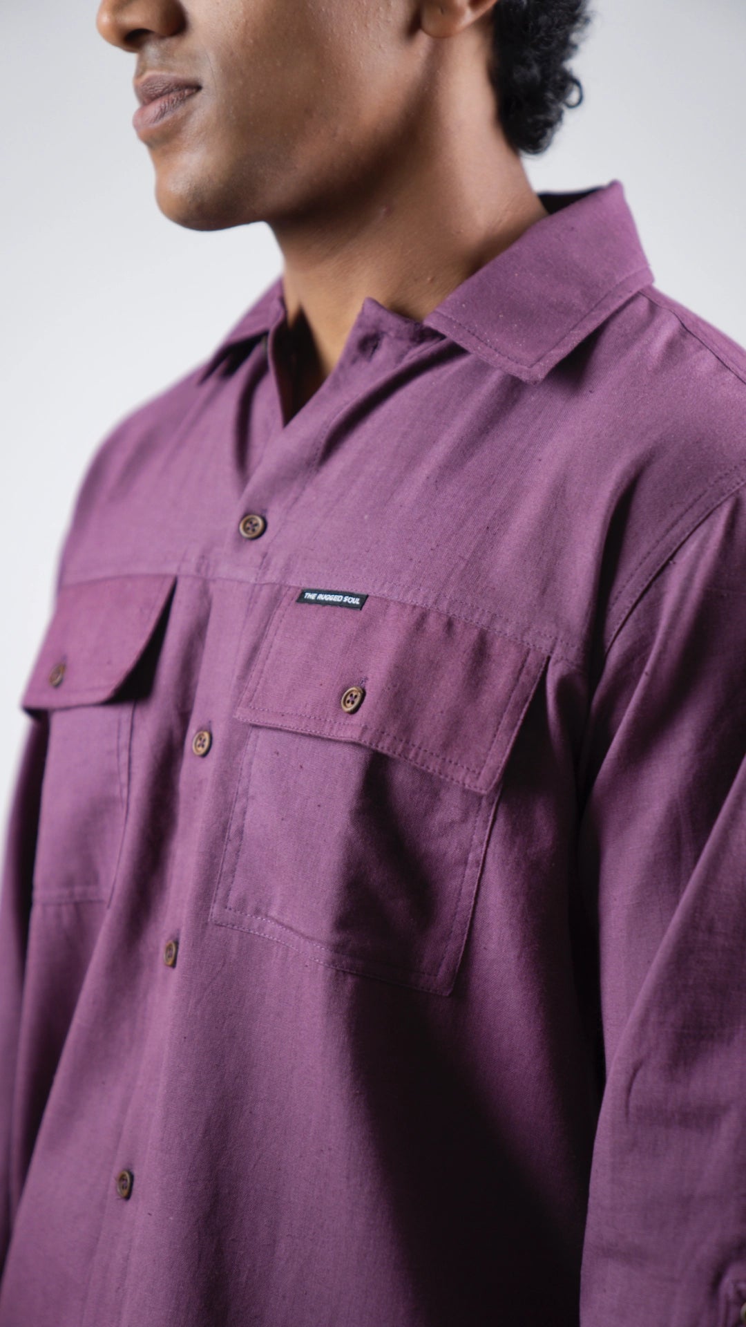 Close-up of a person wearing a purple shirt with a brand logo on a white background