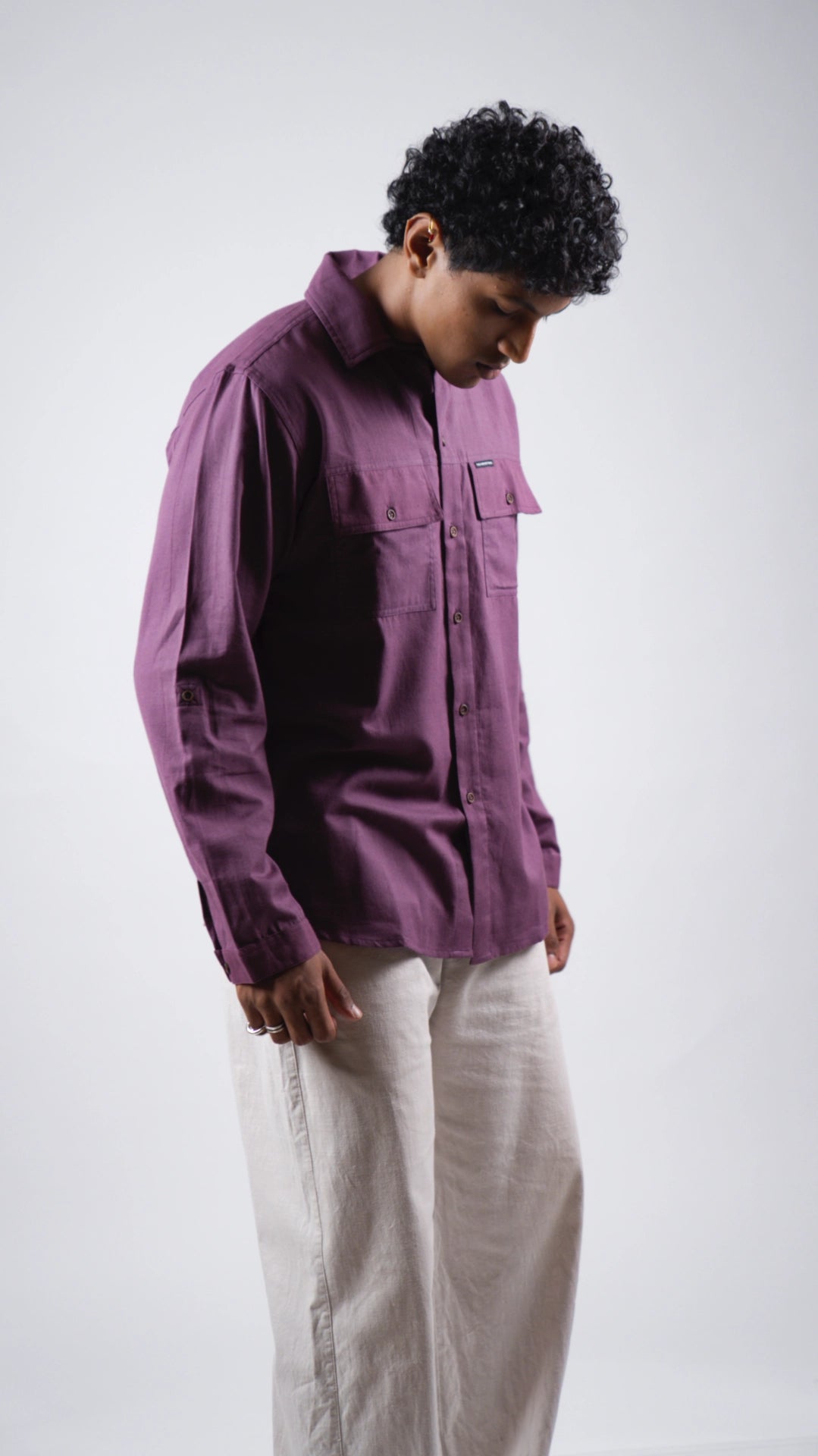 Person wearing a purple jacket and light-colored pants on a white background