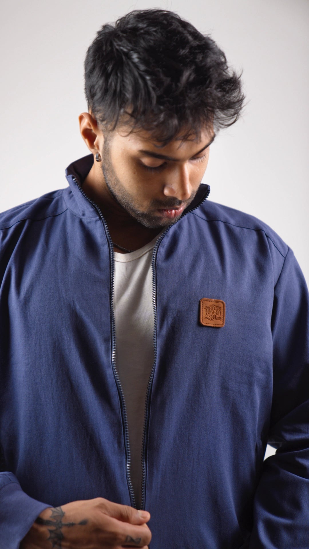 Man wearing a blue jacket with a brown patch on a white background