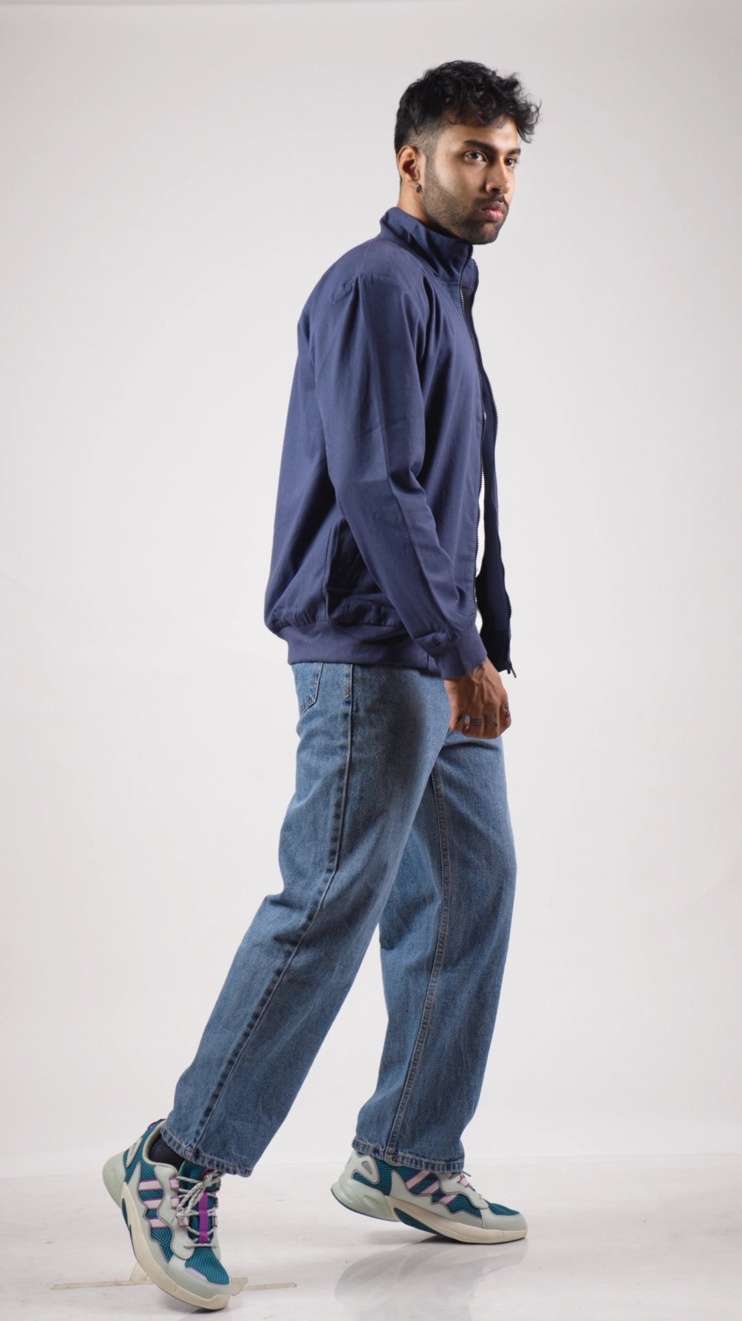 Man wearing a blue jacket and jeans on a white background