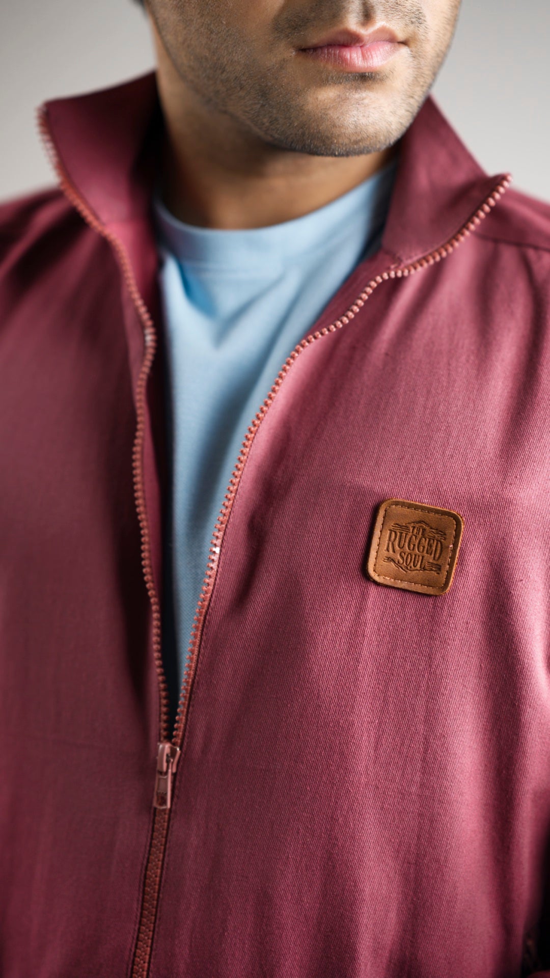 Closeup of a man wearing a deep garnet-coloured cotton twill jacket