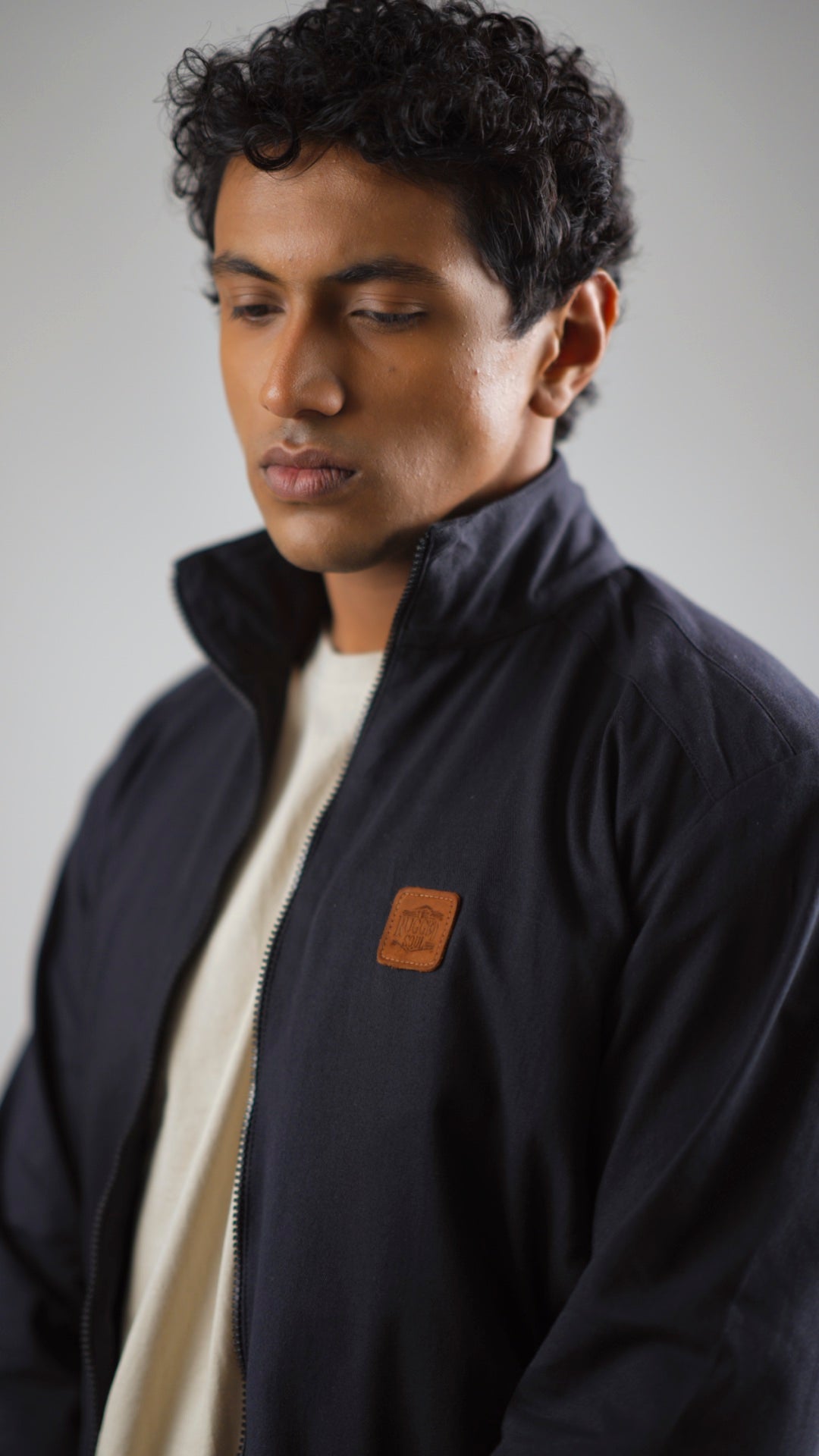 Closeup of a man wearing a midnight navy cotton twill jacket on a light coloured pant and shirt