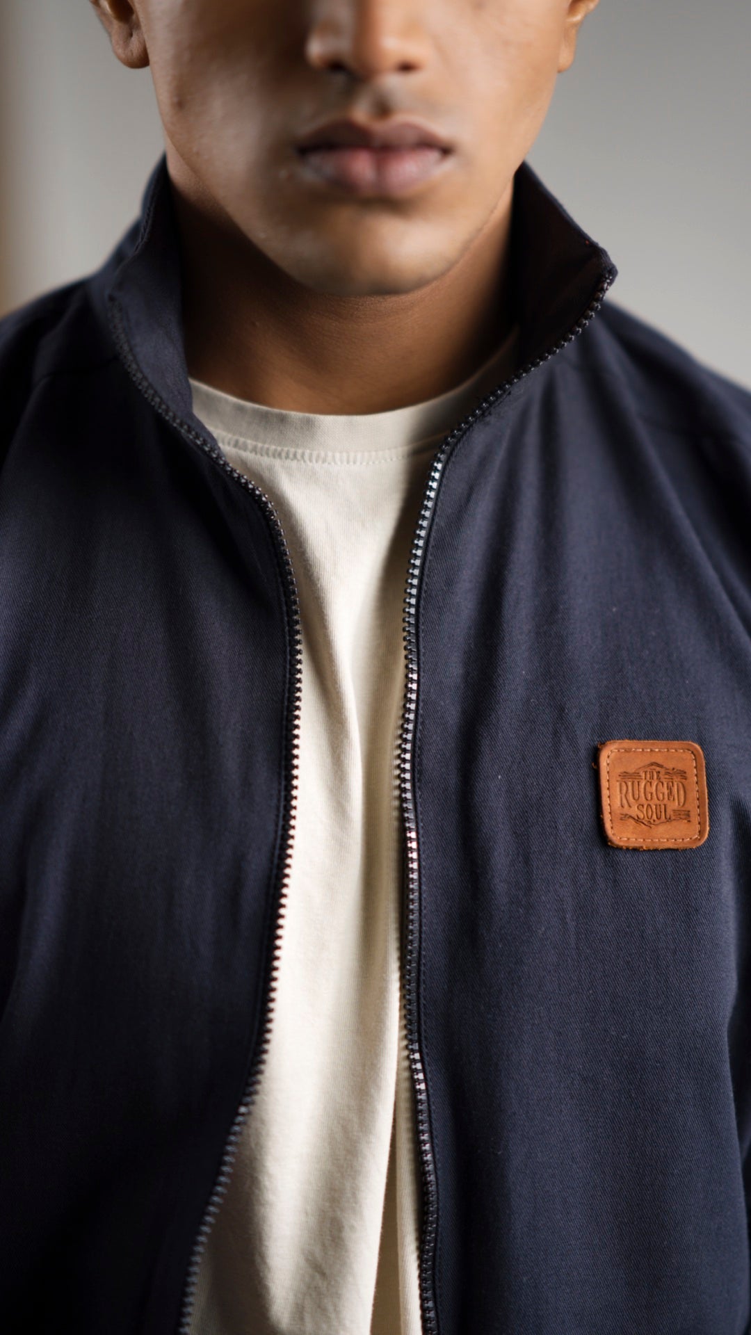 Closeup of a man wearing a midnight navy cotton twill jacket on a light coloured pant and shirt