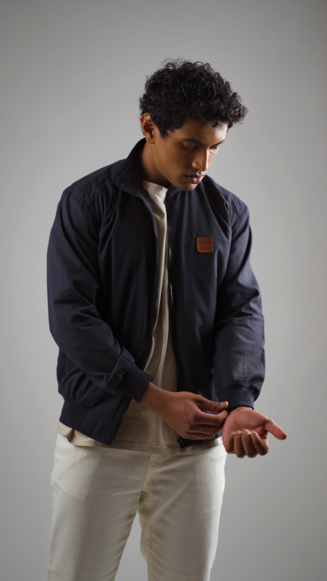 A man wearing a midnight navy cotton twill jacket on a light coloured pant and shirt