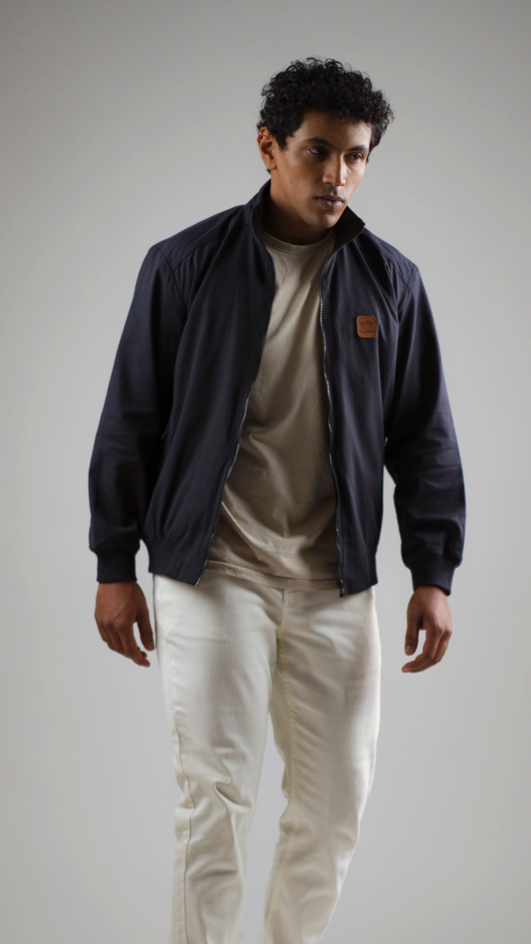 A man wearing a midnight navy cotton twill jacket on a light coloured pant and shirt