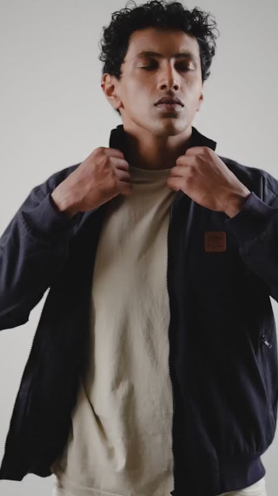 Video of a man wearing a midnight navy cotton twill jacket on a light coloured pant and shirt