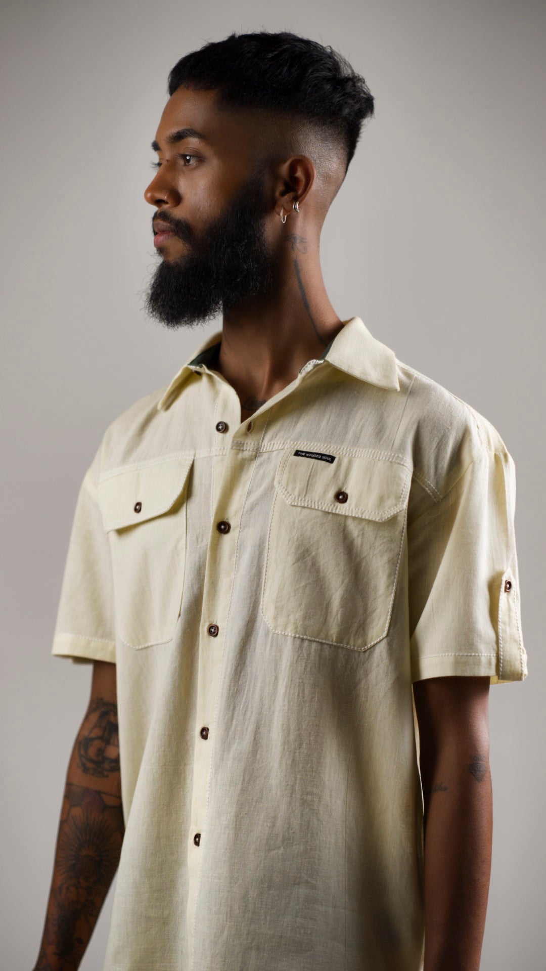 Man posing in an alabaster white cotton linen shirt with contrast stitching and patch pockets