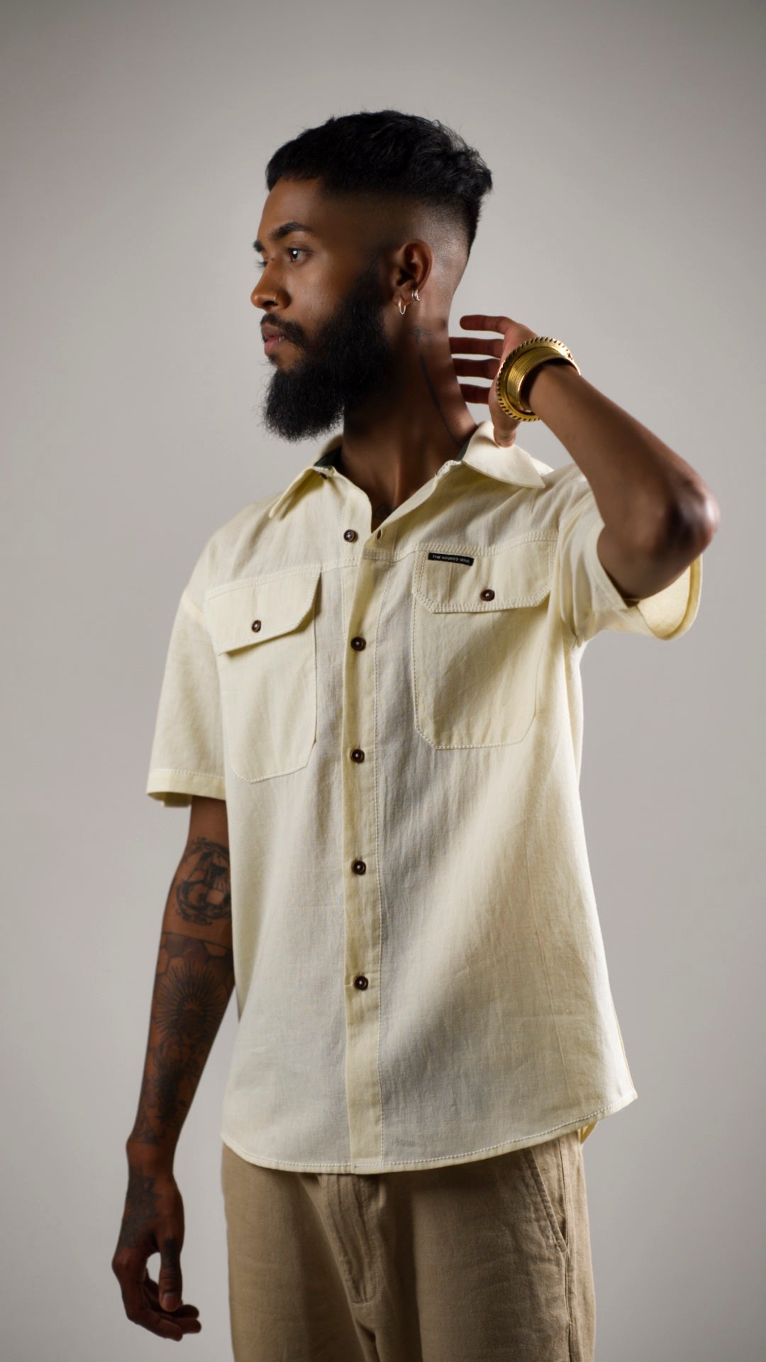 Man posing in an alabaster white cotton linen shirt with contrast stitching and patch pockets