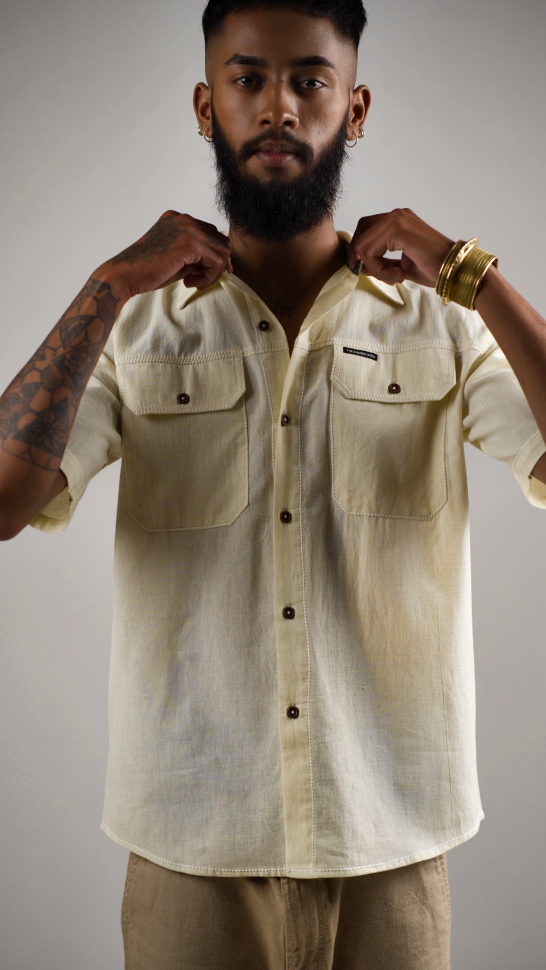 Man posing in an alabaster white cotton linen shirt with contrast stitching and patch pockets