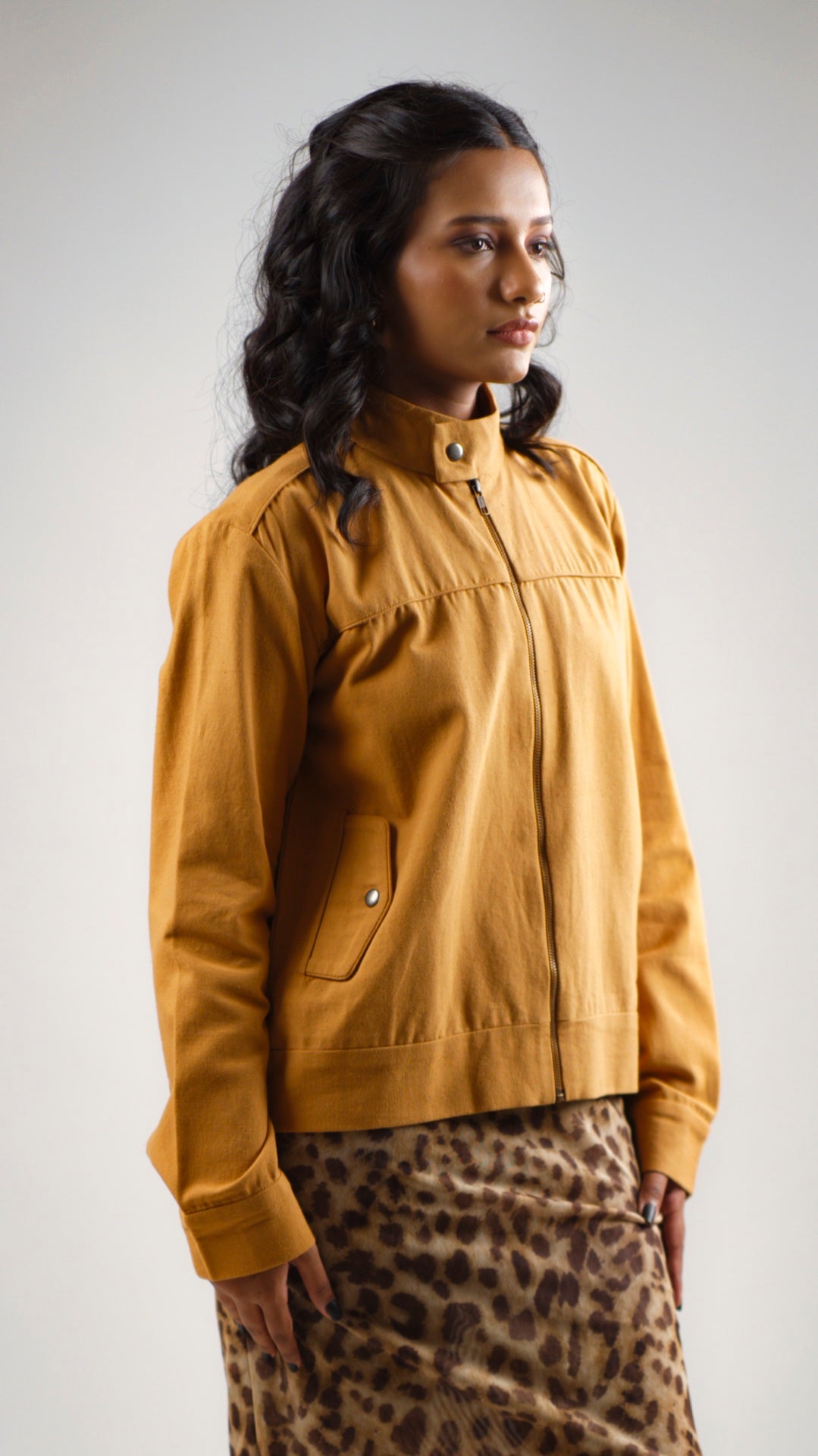 Woman wearing a mustard coloured cotton canvas jacket over a leopard print