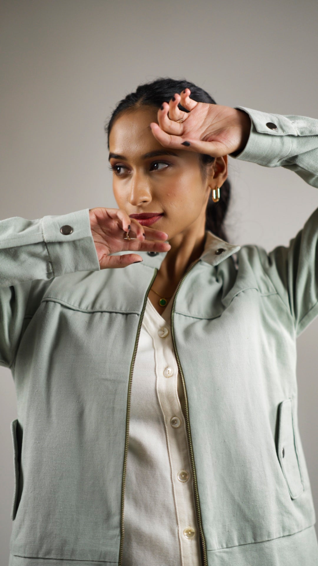 Closeup of a woman posing in an olive sage coloured cotton canvas jacket with welt pockets