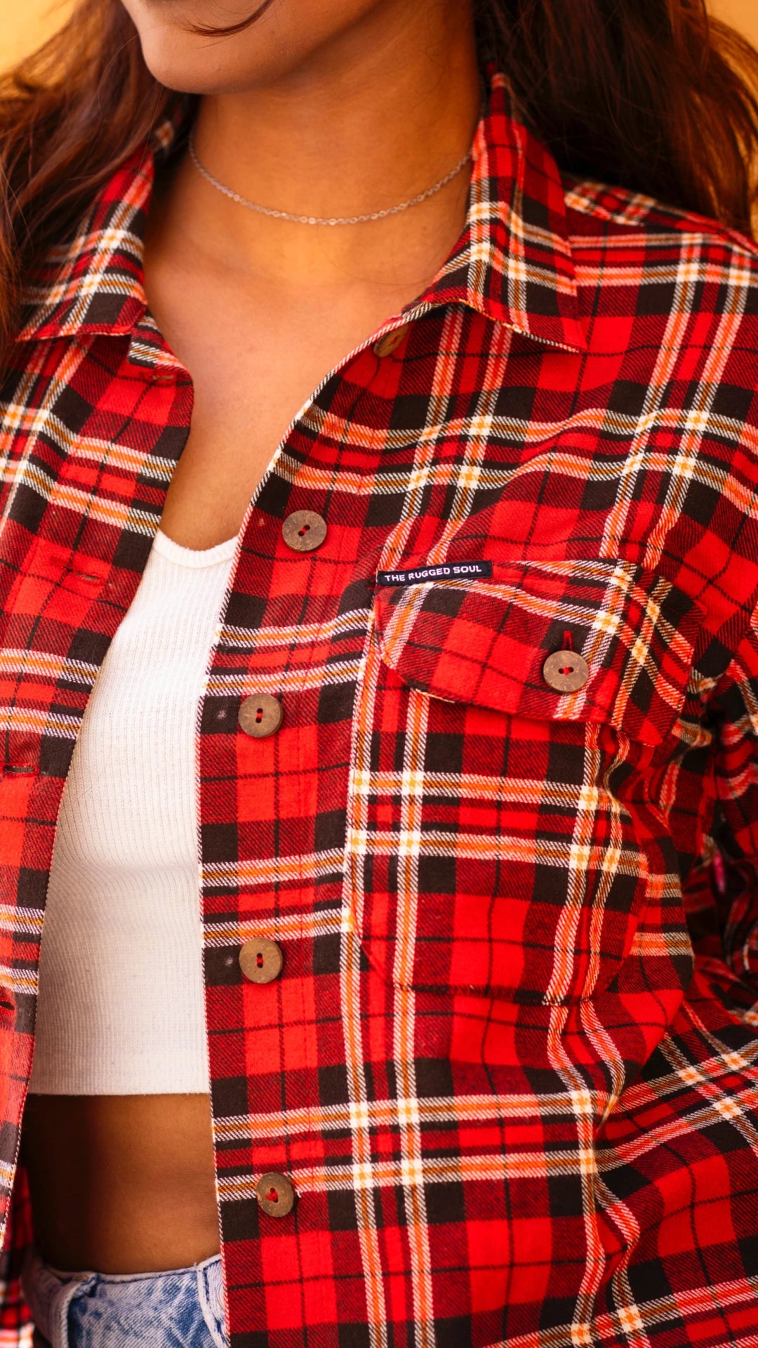 Red and black plaid shirt worn by a person, with a visible brand logo.