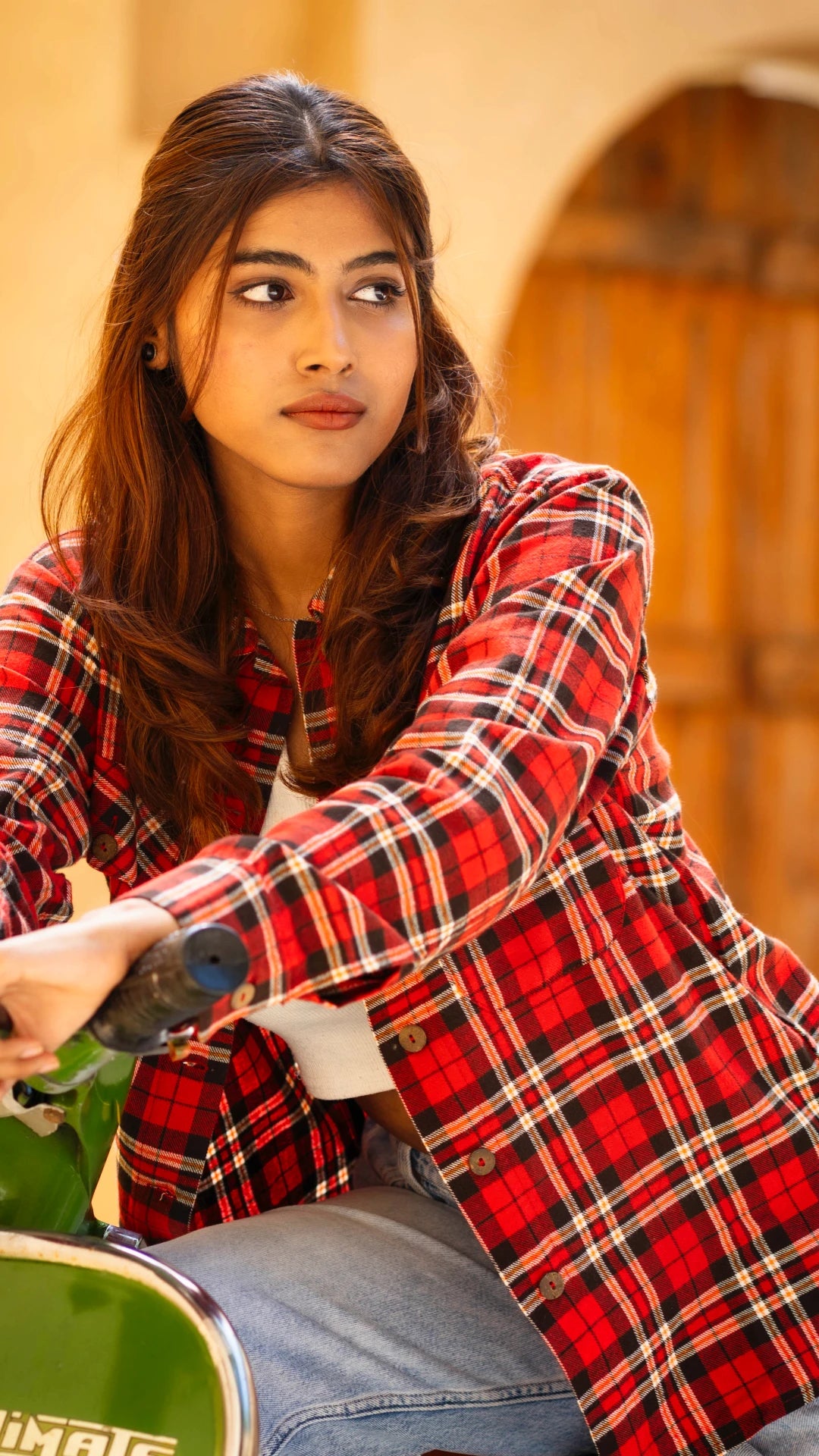 Woman wearing a red plaid shirt sitting on a scooter with a blurred background