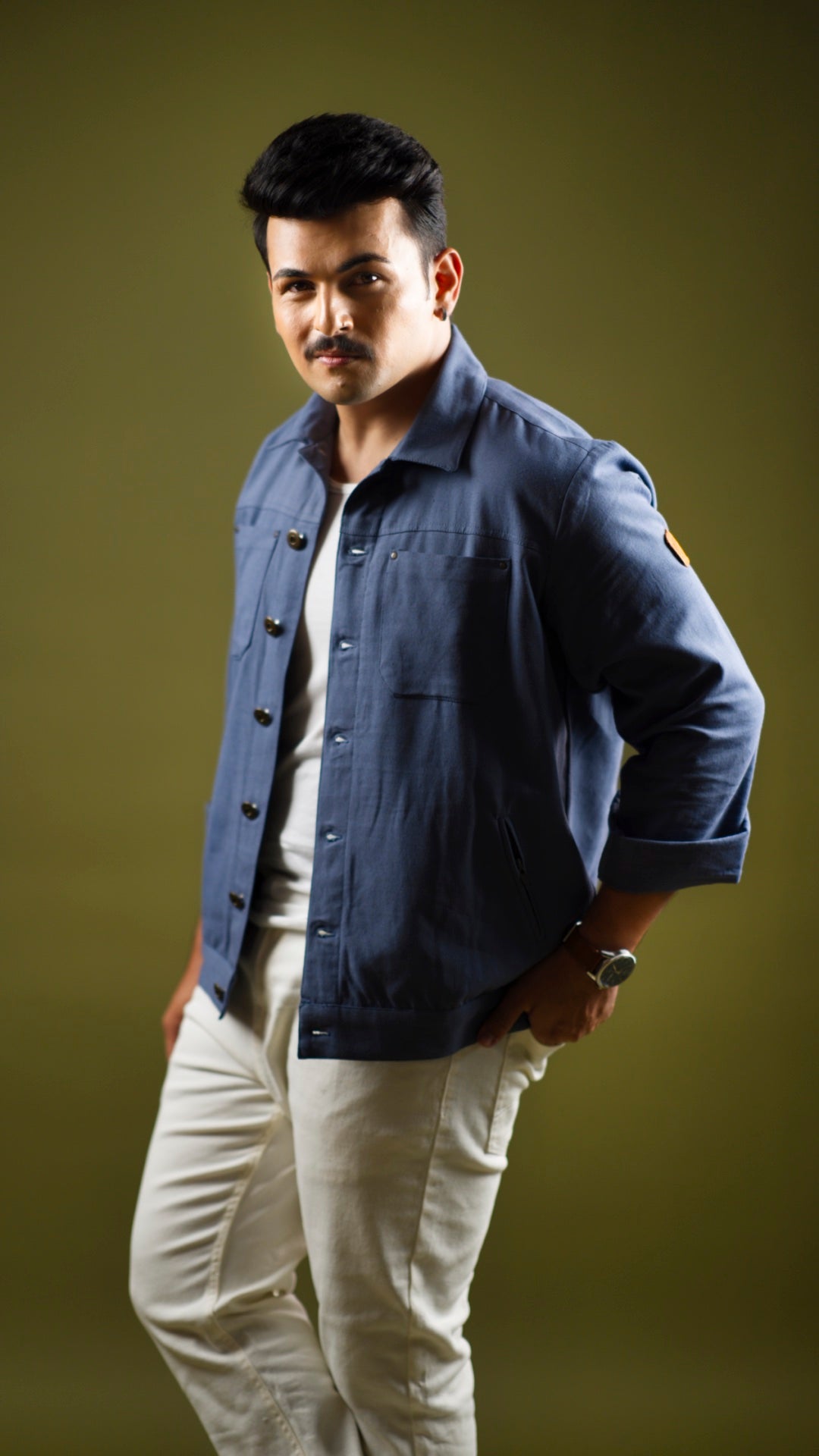 A man wearing a sapphire blue cotton canvas jacket with patch pockets, standing against a green background.