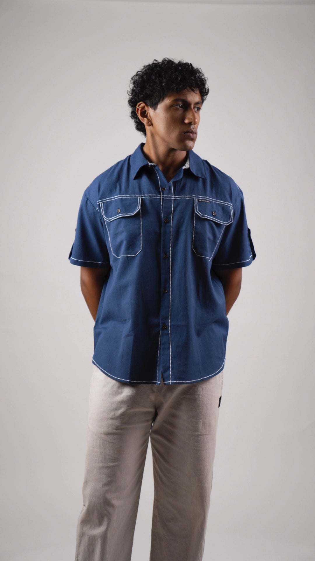 Person wearing a blue cotton linen half-sleeved shirt and beige pants against a plain background